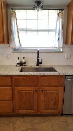 a kitchen with wooden cabinets and stainless steel dishwasher in the center, next to a window