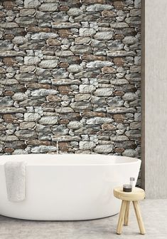 a white bath tub sitting next to a wall with stone walls on it's sides