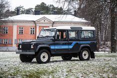 a black and blue jeep parked in front of a red brick building with snow on the ground