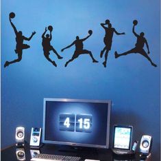 a computer desk with a monitor, speakers and a basketball wall decal on it