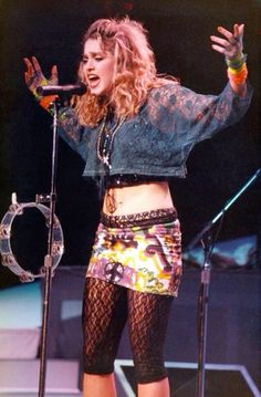 a woman standing on top of a stage with her hands in the air and holding a microphone