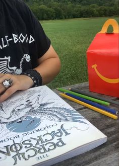 a person sitting at a table with a book and pencils in front of them