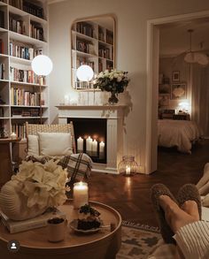 a living room filled with furniture and bookshelves next to a fire place covered in candles