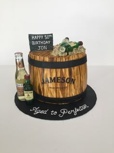 a birthday cake made to look like a barrel with liquor bottles on top and a sign that says happy 50th jon