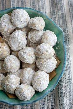 a blue bowl filled with snowball cookies on top of a table