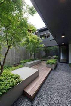 an outdoor area with benches and plants on the ground, along with graveled walkways