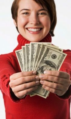 a woman in a red sweater is holding money and smiling at the camera with both hands