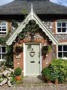 a brick house with potted plants and flowers around the front door on a sunny day