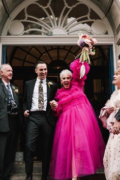 a woman in a pink dress standing next to two men