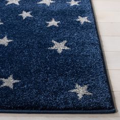 a blue area rug with silver stars on the top and bottom, along with white wood flooring