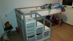 there is a loft bed with shelves underneath it and toys on the floor next to it