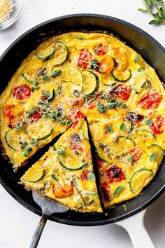 an omelet with zucchini, tomatoes and other vegetables in a skillet