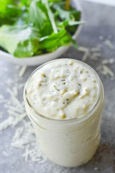 a glass jar filled with food next to a salad