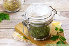 a jar filled with green herbs sitting on top of a wooden cutting board