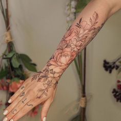 a woman's arm with flowers on it and a cross tattooed on the wrist