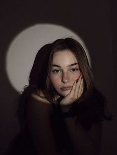 a woman with her hands on her face in front of a white wall and shadow