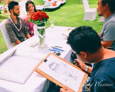 people sitting around a table with drawings and flowers in a vase on top of it