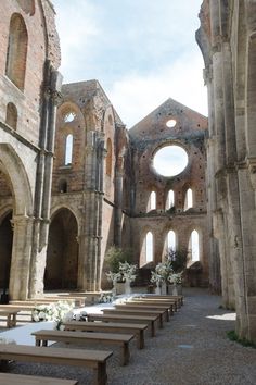 the inside of an old church with benches lined up in rows and flowers on the ground