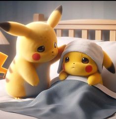 two pikachu stuffed animals sitting on top of a bed next to each other