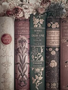 there are many books lined up on the shelf with flowers in front of each book