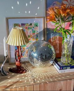 a table with a mirror ball, vase and lamp on it