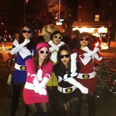 group of women dressed up in costumes posing for the camera on a city street at night