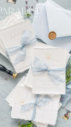 the wedding stationery is laid out on top of each other and tied with blue ribbon