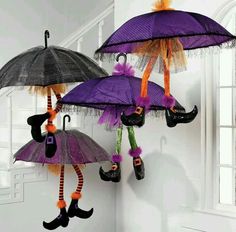 three purple umbrellas hanging from hooks in the shape of people wearing boots and holding umbrellas