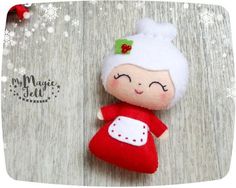 a red and white stuffed doll laying on top of a wooden table next to snowflakes