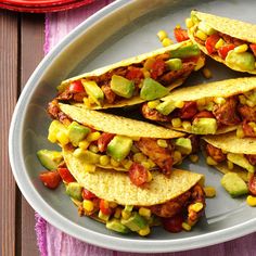 there are five tacos on the plate and one is filled with meat, corn, avocado, and tomato