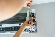 a person is working on an electrical device with wires attached to the side of it