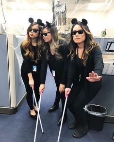 three women dressed in mickey mouse ears pose for a photo with their canes on