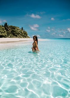 a woman is standing in the water near an island