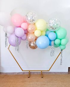 a bunch of balloons that are sitting on a stand in front of a white wall