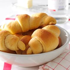 a white bowl filled with croissants sitting on top of a table