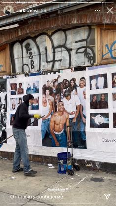 a man standing next to a wall covered in pictures and writing on the side of it