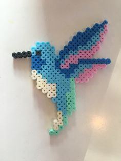 a colorful bird made out of legos on a white surface with one eye open