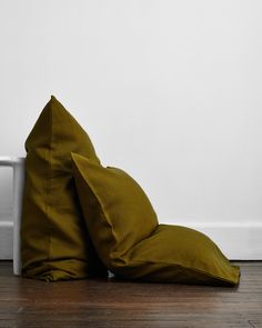 a green pillow sitting on top of a wooden floor next to a white radiator