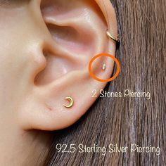 an ear piercing is shown with two small rings on top of the ear, and one smaller