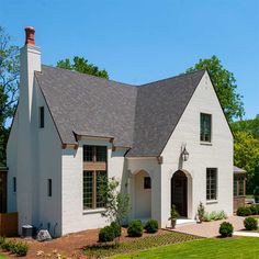 a large white house with two story windows and a brick chimney in the front yard