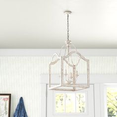 a chandelier hanging from the ceiling in a room with striped walls and white trim