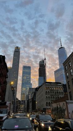 a city street filled with lots of traffic and tall buildings at sunset or dawn in the distance