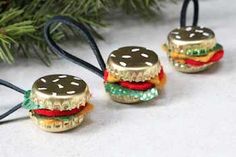 three miniature hamburgers are sitting next to a christmas tree ornament on a table