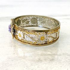 Gorgeous Antique Two Tone Edwardian Filigree Bangle Bracelet with Lavender Glass Stone This is a spectacular antique Edwardian to Art Deco hinged bangle bracelet. It is unique in many ways. The lovely floral pattern is incorporated into a vertical open pattern. The flowers are rhodium plated with gold plated centers. The edges and frame are yellow gold plated. The center is the clasp, a hinged gate-type closure with a hidden flat hook. The stone is unique. It looks oval at first glance but it is Filigree Bangle, Sterling Silver Bangle Bracelets, Bangle Bracelet Set, Jewelry Tags, Silver Bangle Bracelets, Sterling Silver Bangles, Pearl Gemstone, Hinged Bangle, Faceted Glass