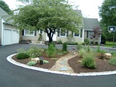 a driveway with landscaping around it in front of a house