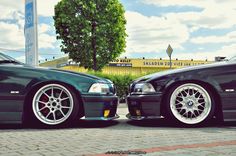 two cars parked next to each other in front of a building with a sky background