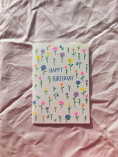 a birthday card with flowers on it sitting on top of a sheet of pink paper