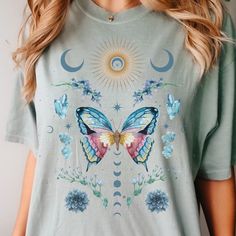 🩴 Beautiful Watercolor Whimsigoth Butterfly Shirt. Celestial figures, florals, crystals, moon and stars surround a gorgeous butterfly on this t-shirt. Perfect gift for fans of Goblincore, Fairy Core, Cottage Core, and Light Academia. 🩴 Click here to view our shop for more great designs --- https://www.etsy.com/shop/GraceAndFlipFlops Click on the ❤️ to see our new designs as they arrive. 🩴 Comfort Colors T-Shirt - The unisex cotton tee is the perfect staple of any wardrobe. The Unisex relaxed Fairycore Short Sleeve Tops For Spring, Summer Fairy Grunge T-shirt With Crew Neck, Fairy Grunge Graphic T-shirt For Summer, Summer Fairycore Top With Graphic Print, Cotton Fairycore T-shirt For Summer, Summer Fairycore Cotton T-shirt, Fairycore Cotton T-shirt With Graphic Print, Spring Fairycore Graphic Print T-shirt, Fairycore Graphic Print Cotton T-shirt