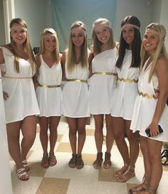 four girls in white dresses posing for the camera with their arms around each other while wearing gladia sandals