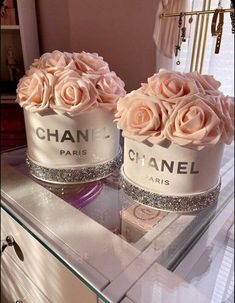 two pink roses sitting on top of a table next to bottles of chanel perfume